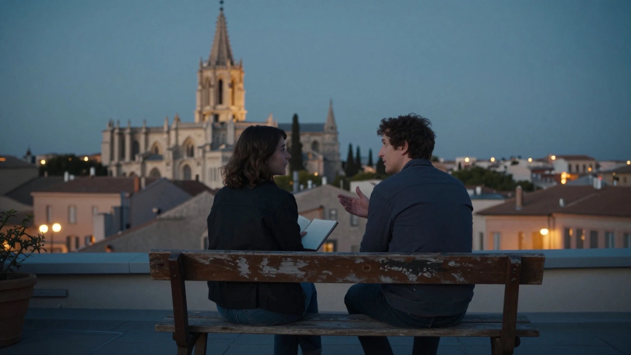 Two people sit quietly on a rooftop terrace at dusk, overlooking Montpellier&#039;s cathedral with city lights glowing below.